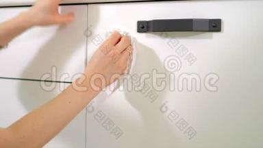女士用海绵和喷雾清洁剂清洗厨房橱柜。